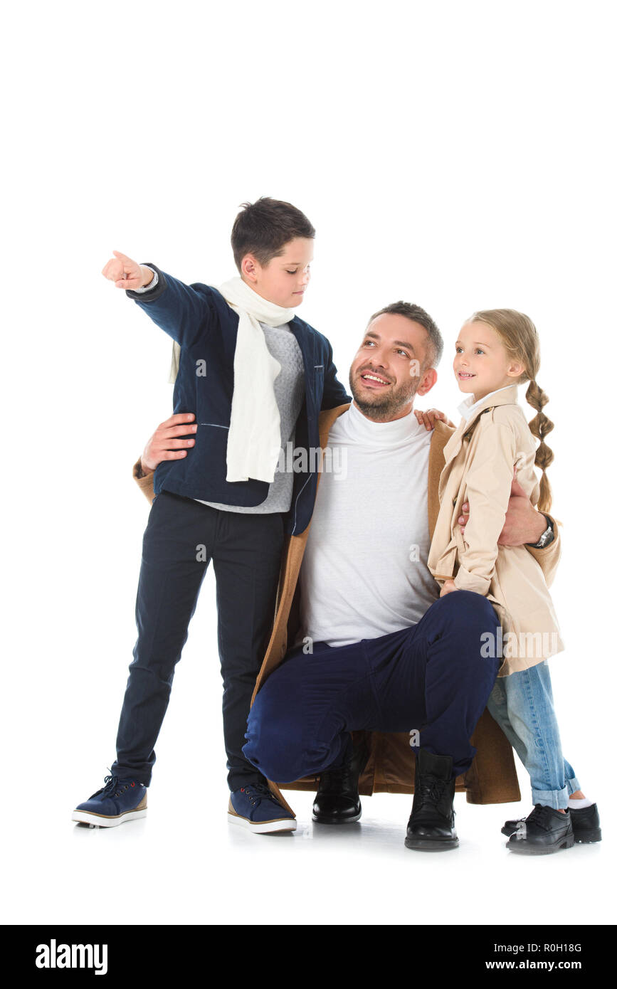 Happy father hugging enfants en tenue d'automne, garçon montrant quelque chose d'isolé sur fond blanc Banque D'Images