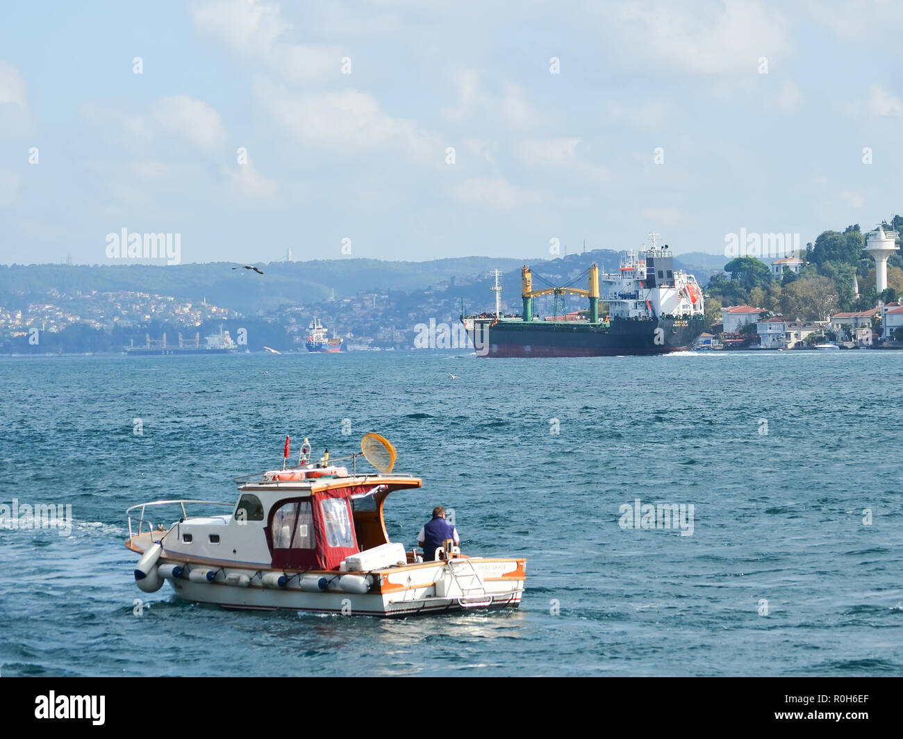 Grand cargo va le long du Bosphore, un petit bateau de pêche avec un pêcheur dans l'avant-plan. Banque D'Images