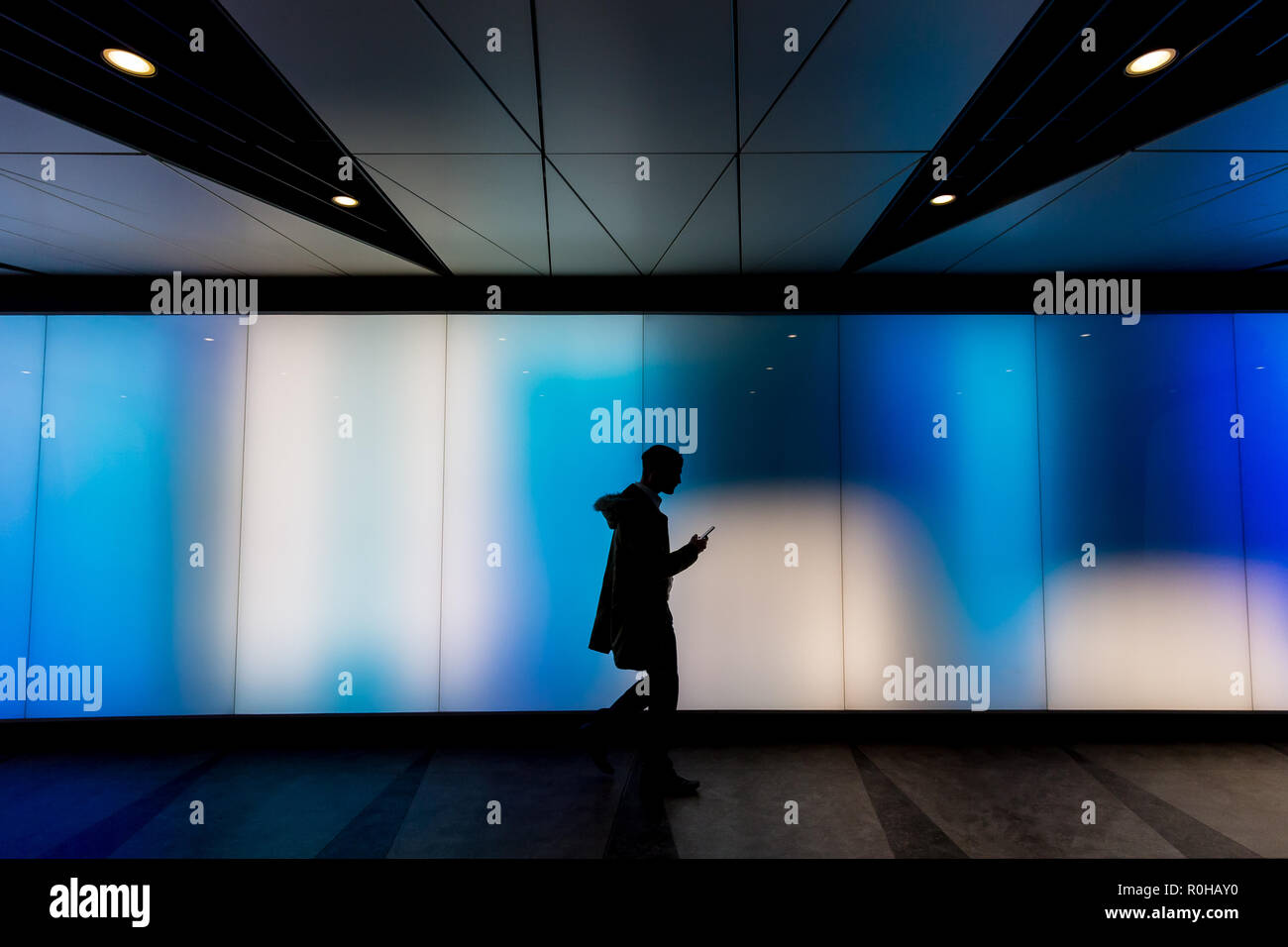Jeune homme marchant à l'aide de téléphone en science-fiction moderne futuriste moody tunnel sombre contexte en ville London lights Banque D'Images