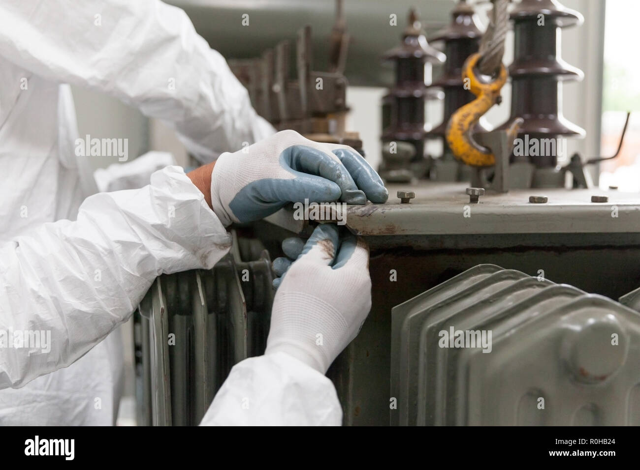 Un homme en blanc, de protection vêtements de travail et des gants, préparation d'un transformateur vieux composants pour le recyclage. La gestion des déchets Banque D'Images