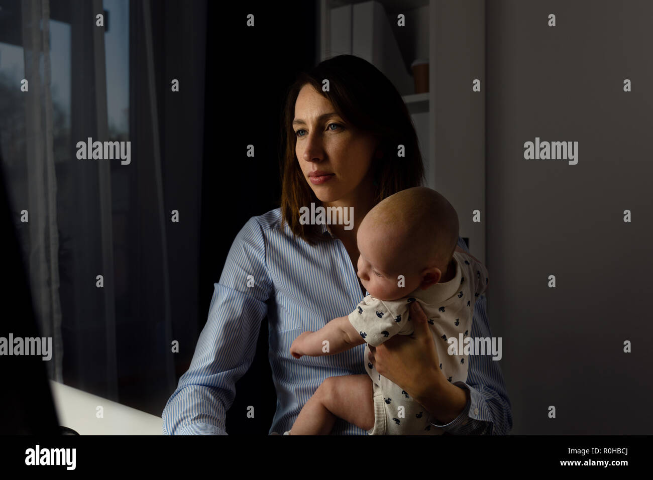 Les femmes d'affaires occupés travaillant dans un bureau avec un bébé sur ses mains. Fin de concept. Banque D'Images