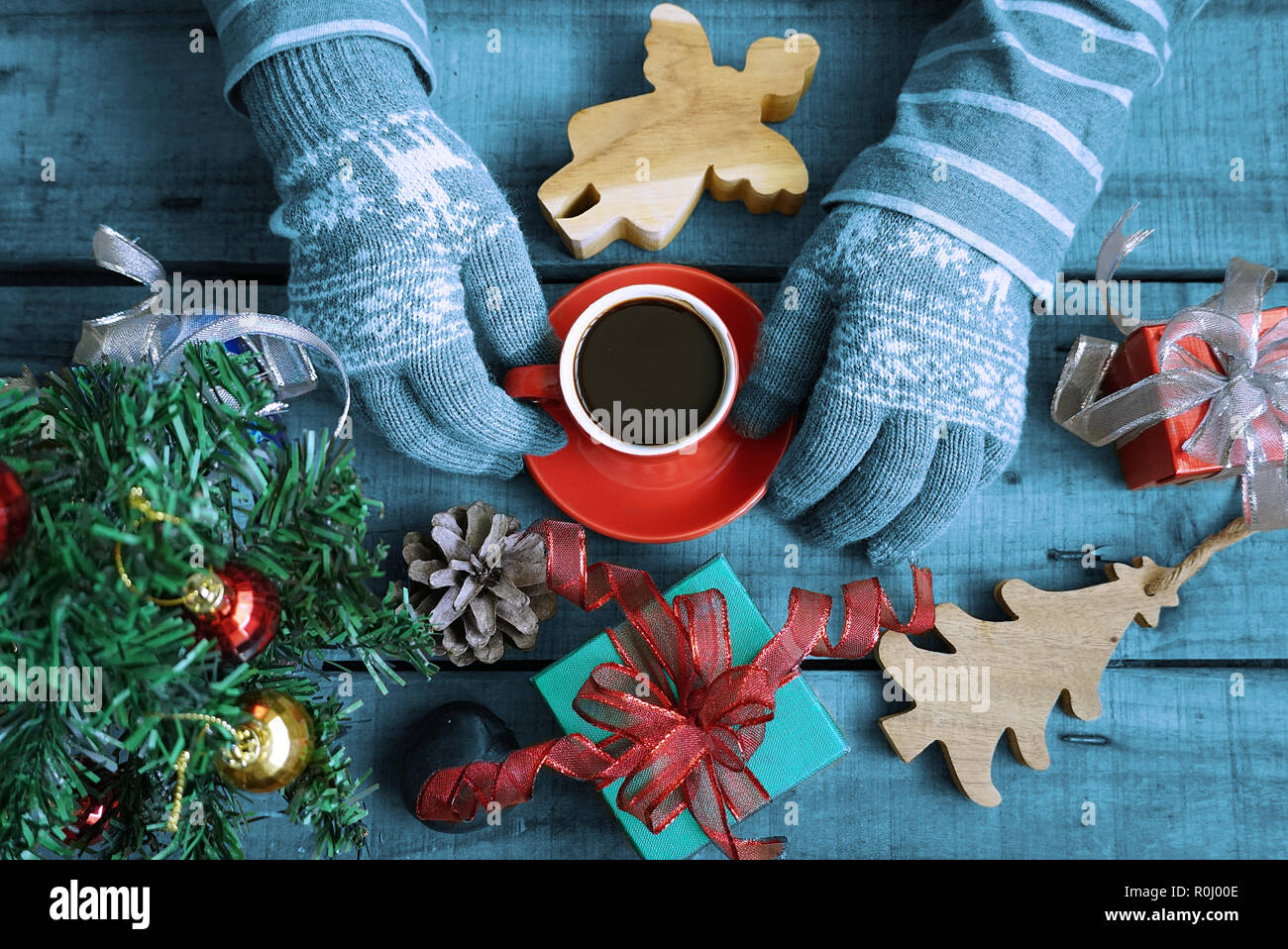Blue theme tourisme Vue de dessus porter des gants et garder au chaud, une tasse à café sur table en bois qui ont des dons décorer thème de Noël Banque D'Images