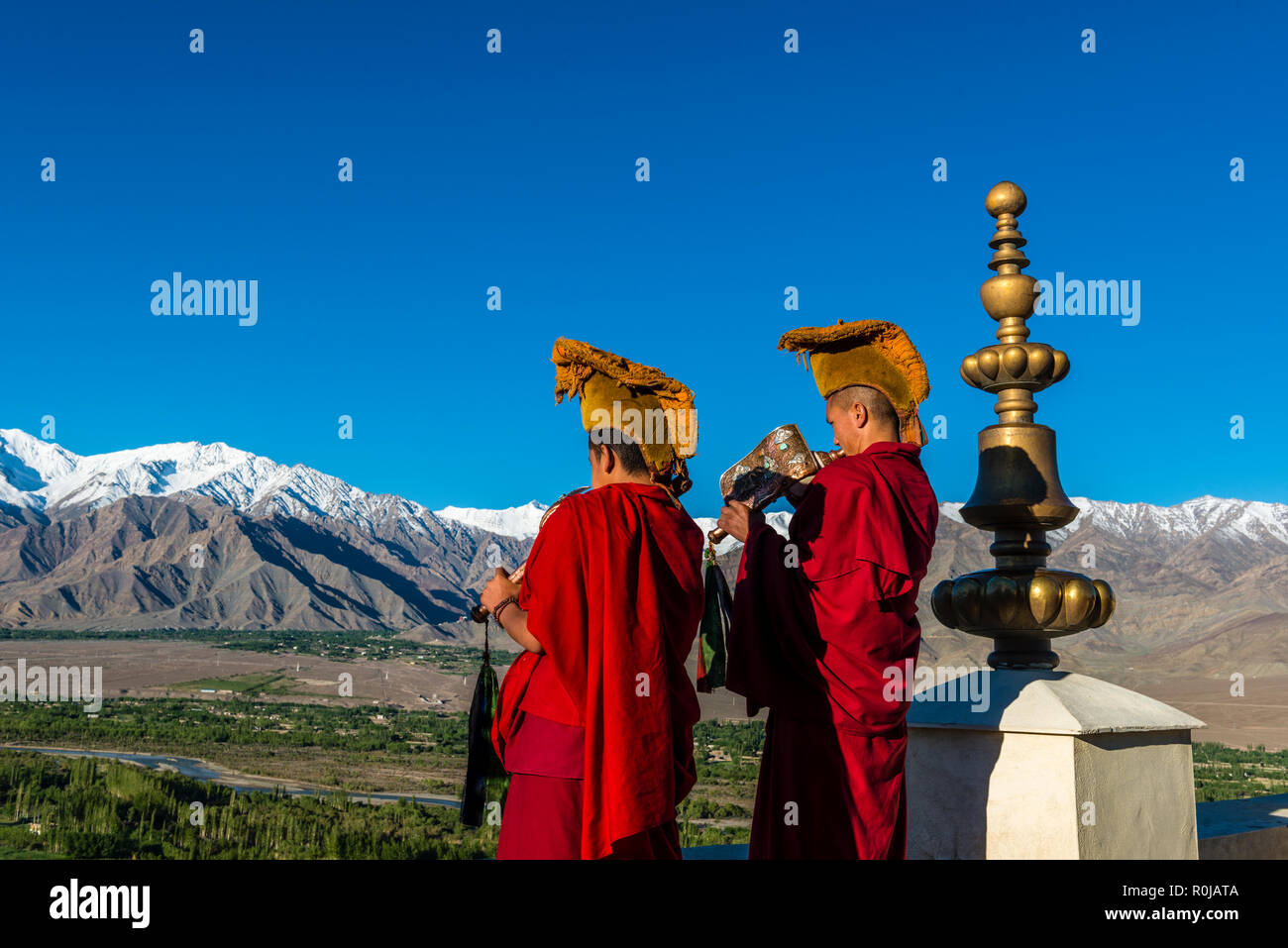 Deux moines vêtus rouge soufflé la coquille corne d'annoncer le matin pooja, prière, sur le toit de Thiksey Gompa, un des plus importants | couvent Banque D'Images