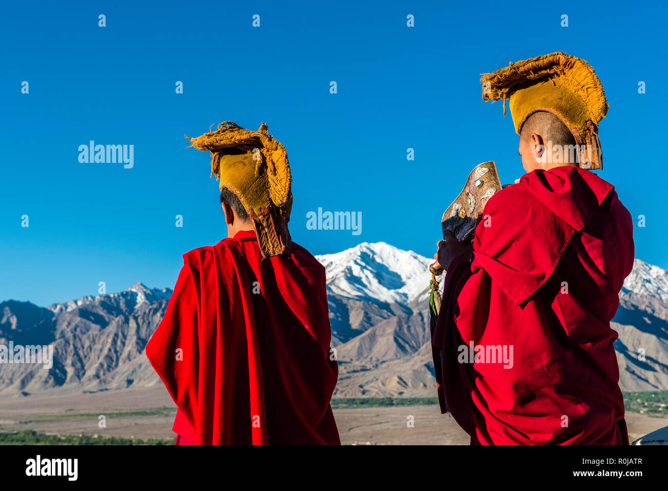 Deux moines vêtus rouge soufflé la coquille corne d'annoncer le matin pooja, prière, sur le toit de Thiksey Gompa, un des plus importants | couvent Banque D'Images