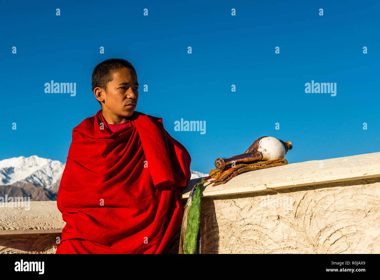 Un moine habillé rouge à la verte jusqu'à la vallée de l'Indus du toit de Thiksey Gompa, un des plus importants monastères du Ladakh Banque D'Images