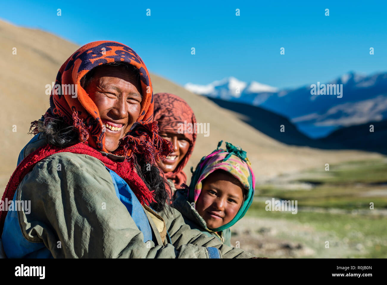 Portraits d'une famille nomade, souriant, dans la région de Tso Moriri Changtang proche avec des montagnes enneigées au loin. Banque D'Images