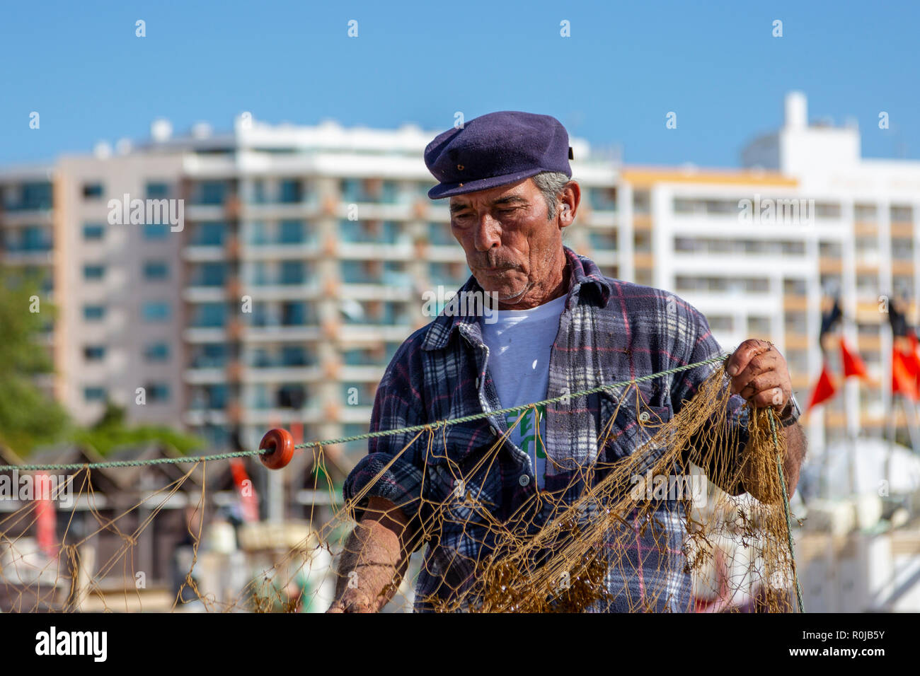 Le pêcheur local qui tend ses filets de pêche sur la plage de Monte Gordo, Algarve, Portugal Banque D'Images