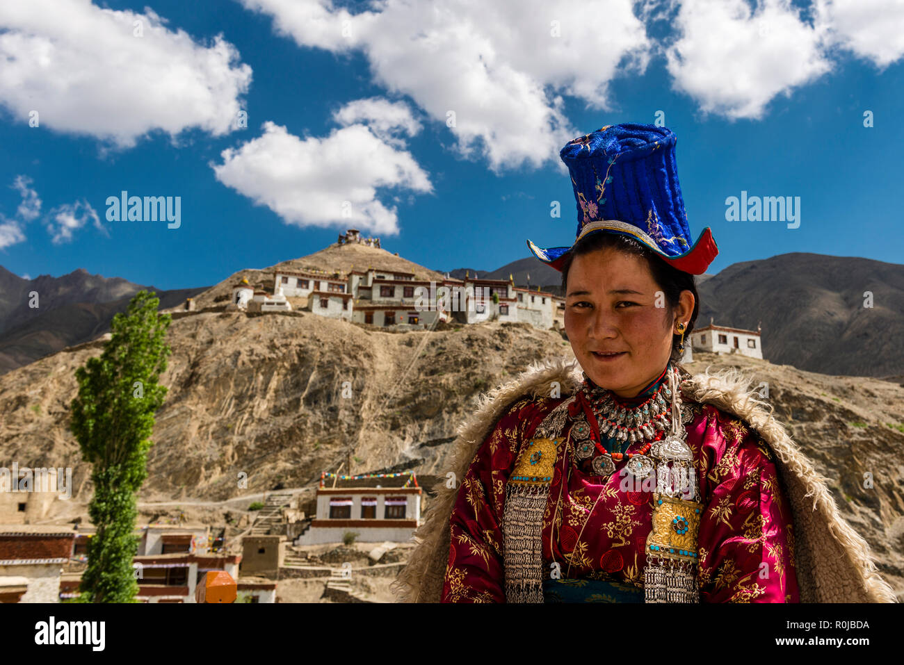 Une femme ladakhis affiche sa robe traditionnelle, Lamayuru Gompa et ciel bleu avec des nuages blancs dans l'arrière-plan Banque D'Images