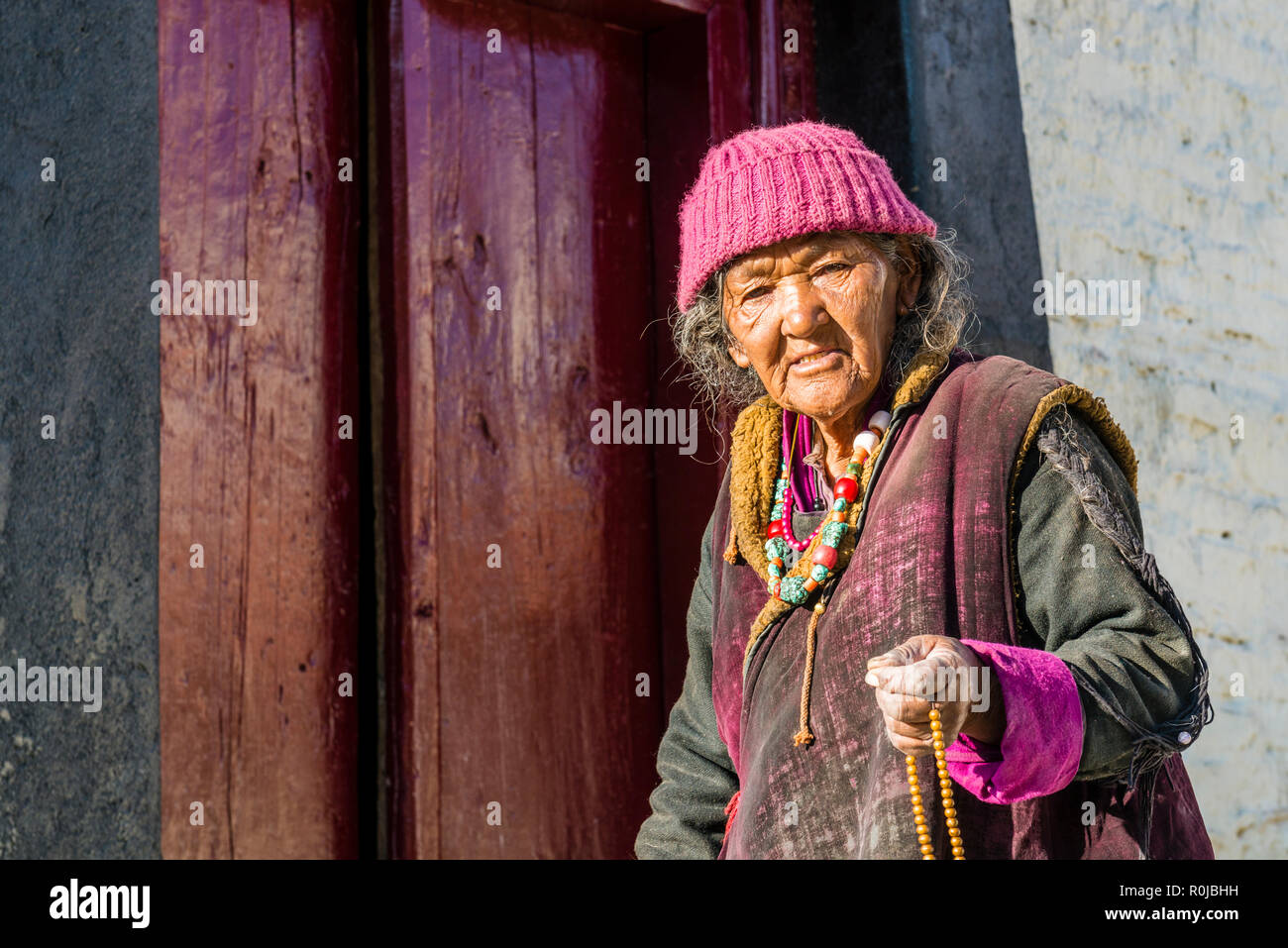 Une vieille femme marche ladakhis autour de Lamayuru Gompa, le plus ancien et le plus grand monastère existant au Ladakh, le déménagement de son beeds Mala pour religeous Banque D'Images