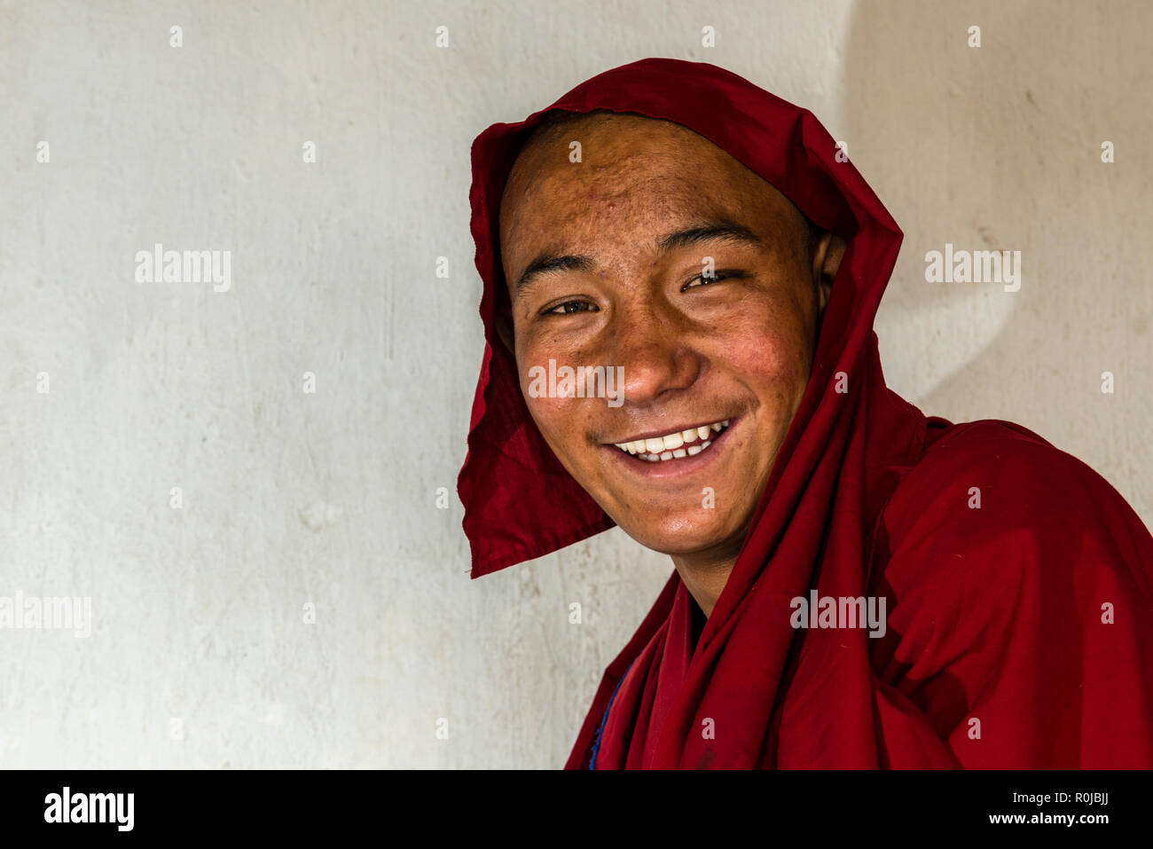 Un portrait d'un moine de Likir Gompa, un des monastères bouddhistes au Ladakh, vêtus de chiffons rouges et souriant. Banque D'Images