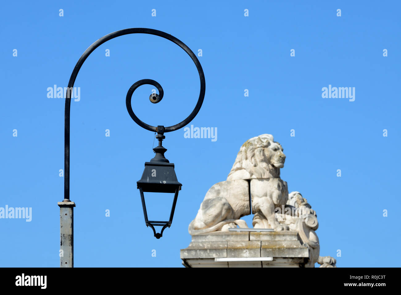 Lumières de rue contemporain ou lampes sculptées en pierre et les Lions au sommet de colonnes ou de l'ancien pont suspendu sur le fleuve Rhône à Arles Provence France Banque D'Images