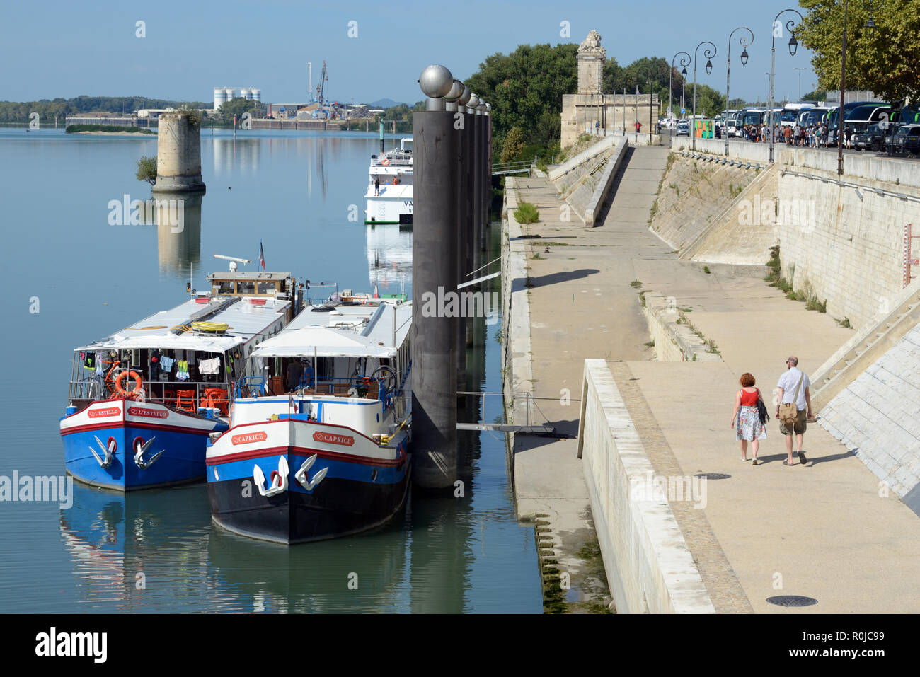 Un couple de touristes à pied le long des berges du Rhône avec les bateaux de croisière ou des chalands amarrés sur le quai Arles Provence France Banque D'Images