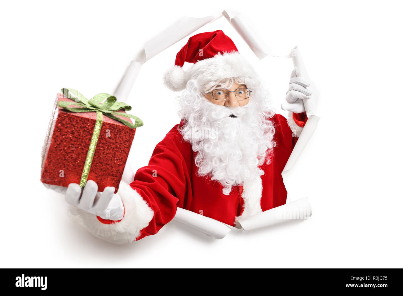 Santa Claus giving a present à travers un trou du papier isolé sur fond blanc Banque D'Images
