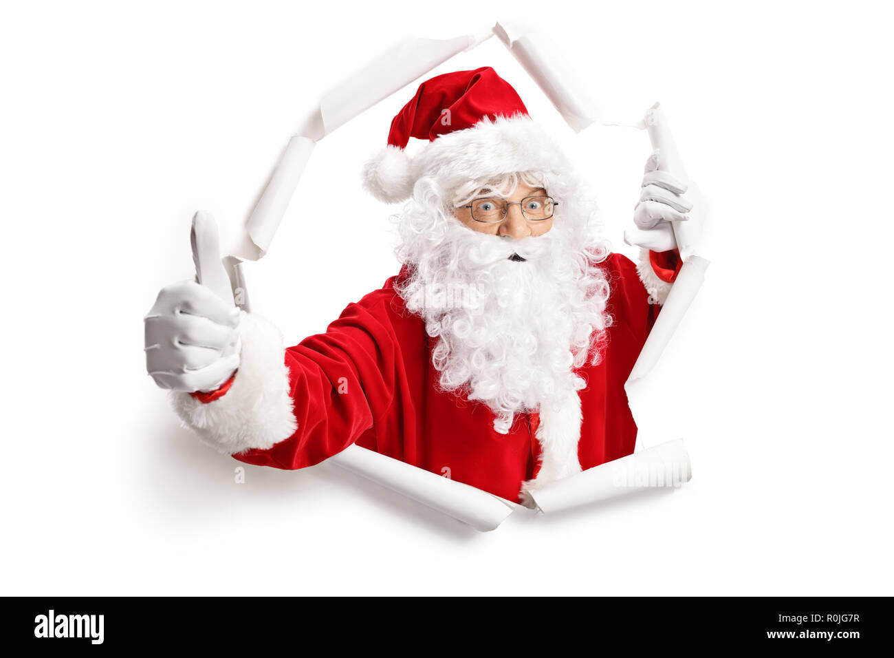 Père Noël faire Thumbs up à travers un trou du papier isolé sur fond blanc Banque D'Images