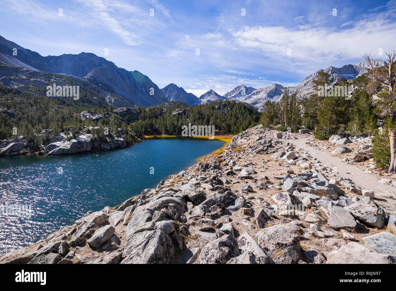 Sentier de randonnée pédestre à la suite de la rive d'un lac alpin entouré par les crêtes rocheuses de l'Est de la Sierra montagnes ; fort peu, le lac Lacs Valley t Banque D'Images