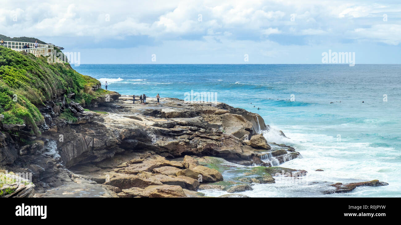 Bondi à Coogee promenade côtière personnes debout sur les rochers de grès au-dessus de l'océan Pacifique Sydney NSW Australie. Banque D'Images