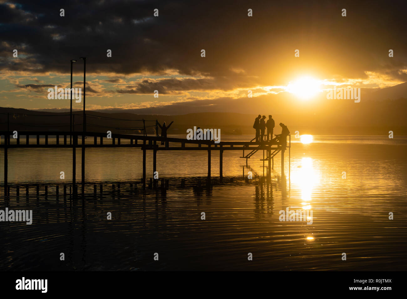 Les gens se détendre à une jetée pendant le coucher du soleil Banque D'Images