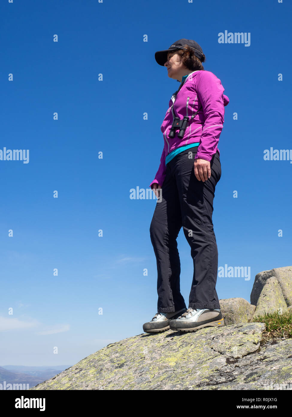 Une dame d'âge mûr à la recherche sur la campagne écossaise à partir d'un point de vue sur les collines élevées au cours d'une randonnée Banque D'Images