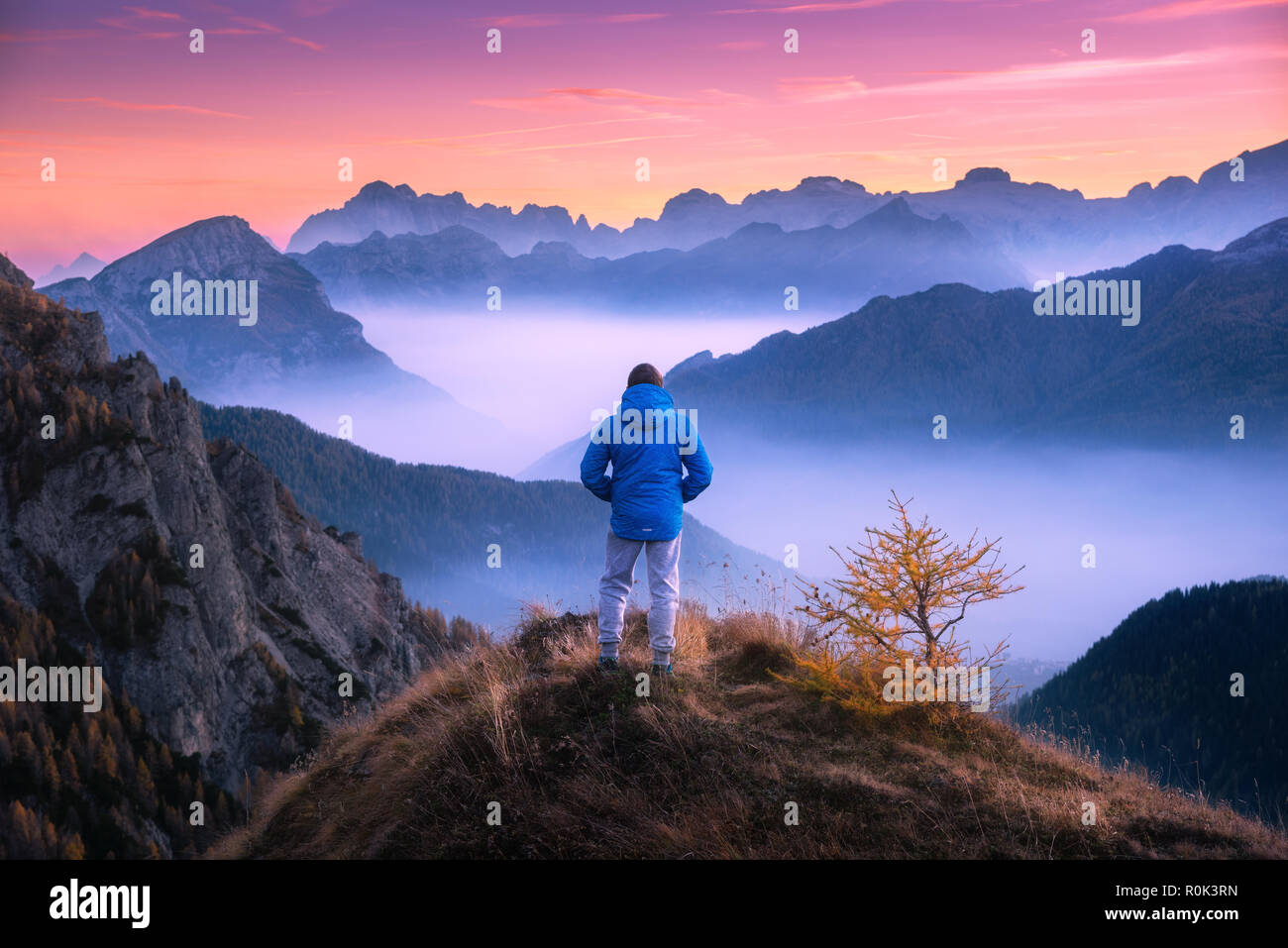L'homme sportif sur le sommet de la montagne à la vallée de montagne avec les nuages bas au soleil colorés à l'automne dans les Dolomites. Paysage avec traveler, foggy h Banque D'Images