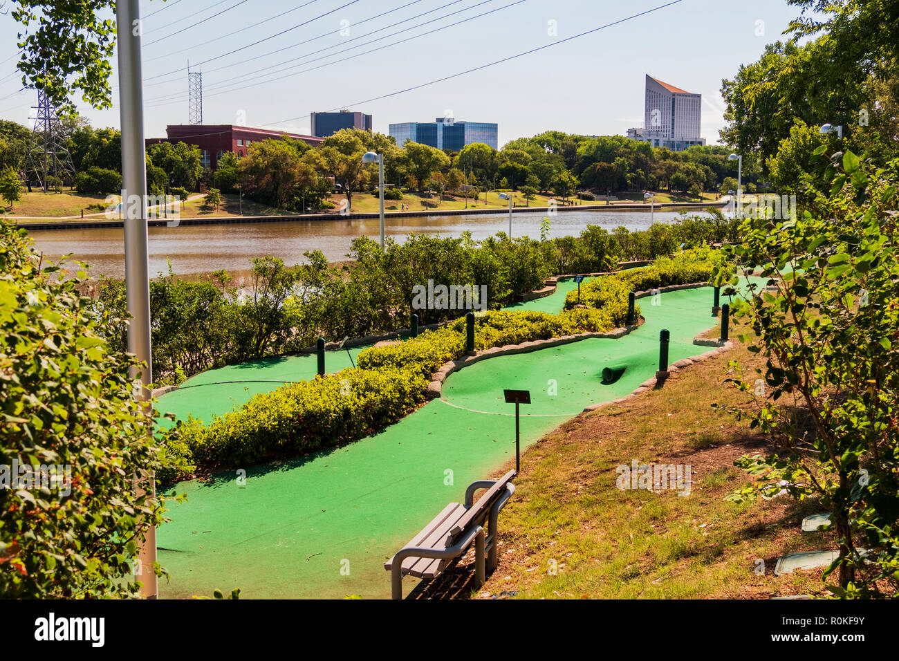 Un golf miniature fonctionnant à côté de la rivière Arkansas avec des bâtiments de la ville en arrière-plan. Promenade le long de la rivière sur la rive opposée. Wichita, Kansas, États-Unis. Banque D'Images