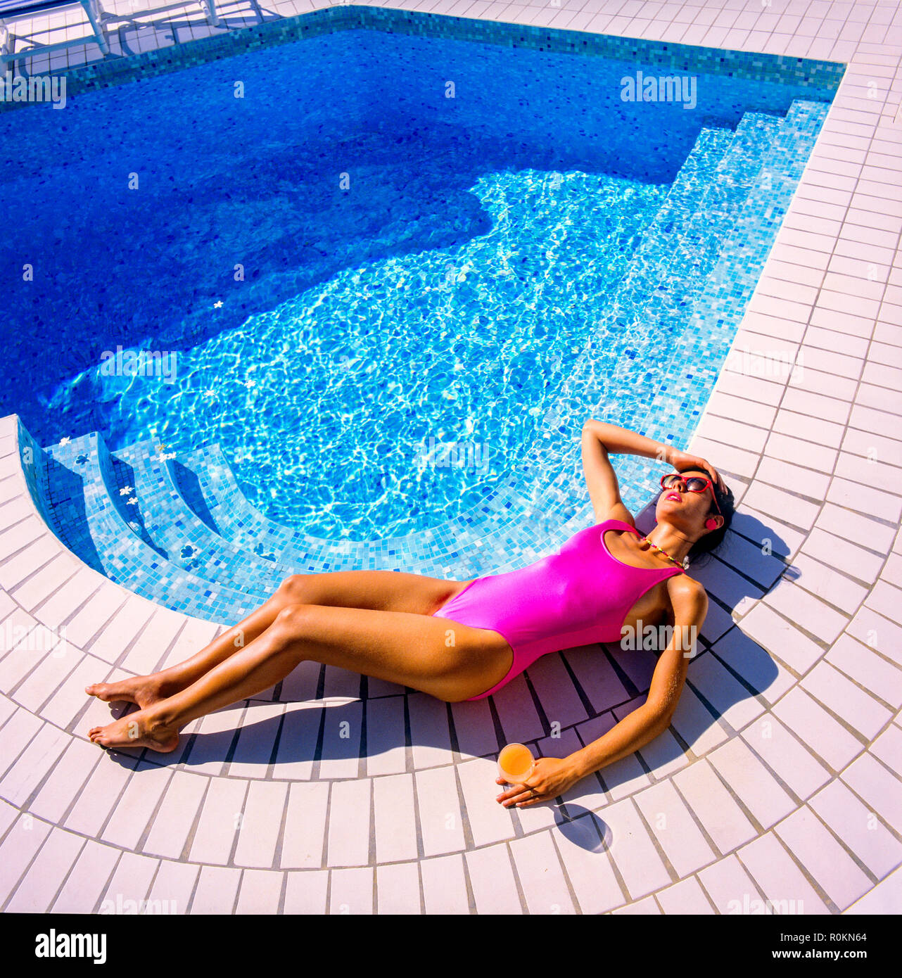 Jeune femme avec maillot de bain de soleil rose au bord de la piscine, piscine, Guadeloupe, French West Indies, Banque D'Images
