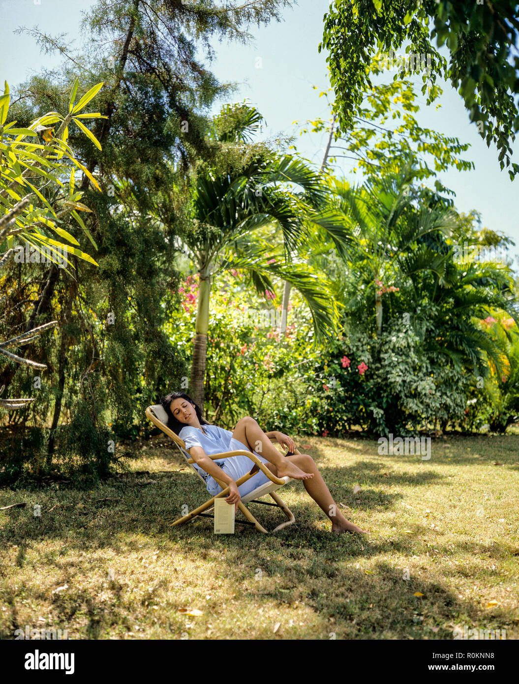 Jeune femme sieste dans une chaise longue, d'un jardin tropical, Guadeloupe, French West Indies, Banque D'Images