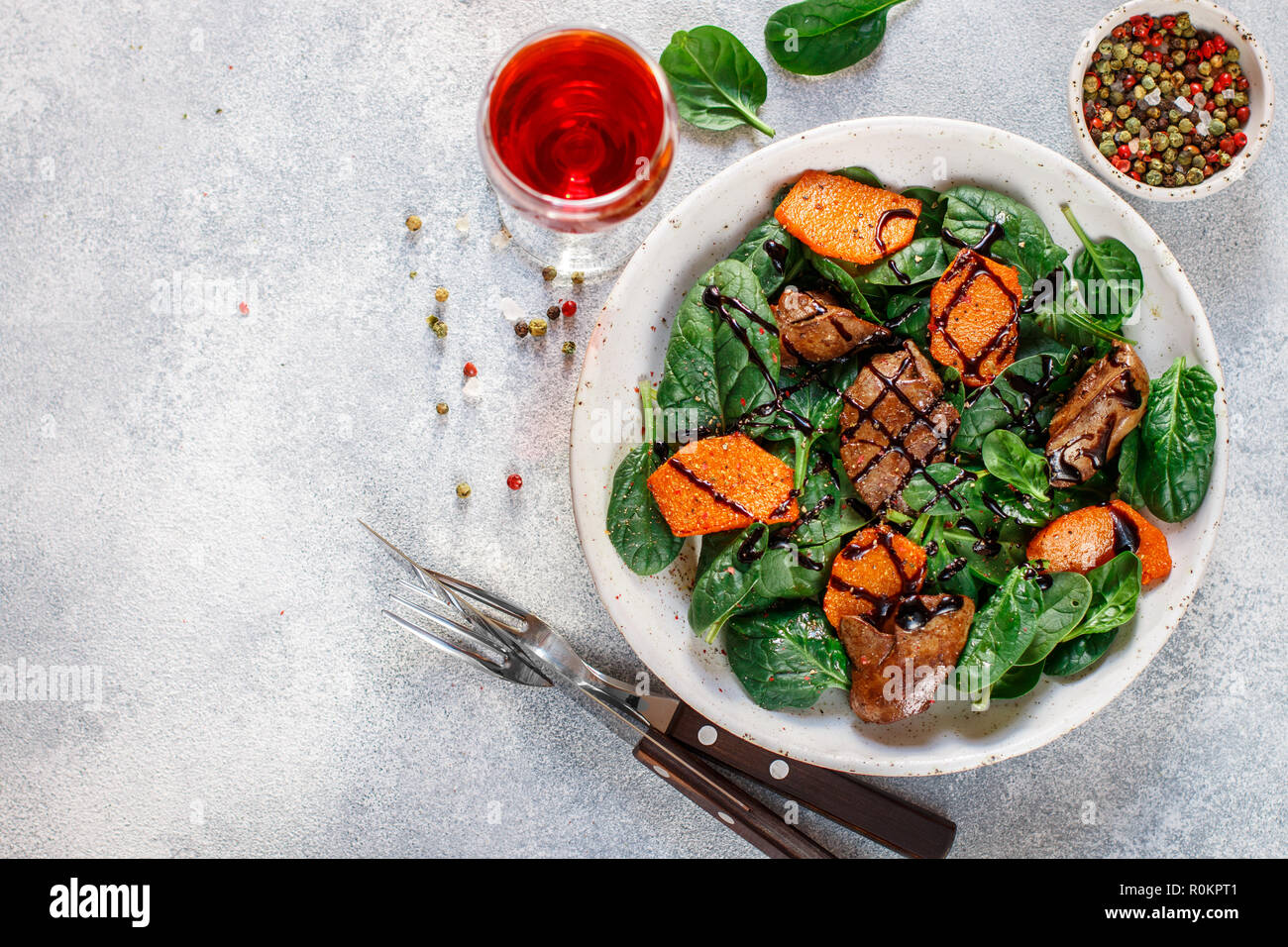 Salade tiède de foie de poulet cuit avec de la citrouille et aux épices et vinaigre balsamique. Délicieux dîner avec du vin rouge pour les gourmets. Selective focus, top vi Banque D'Images