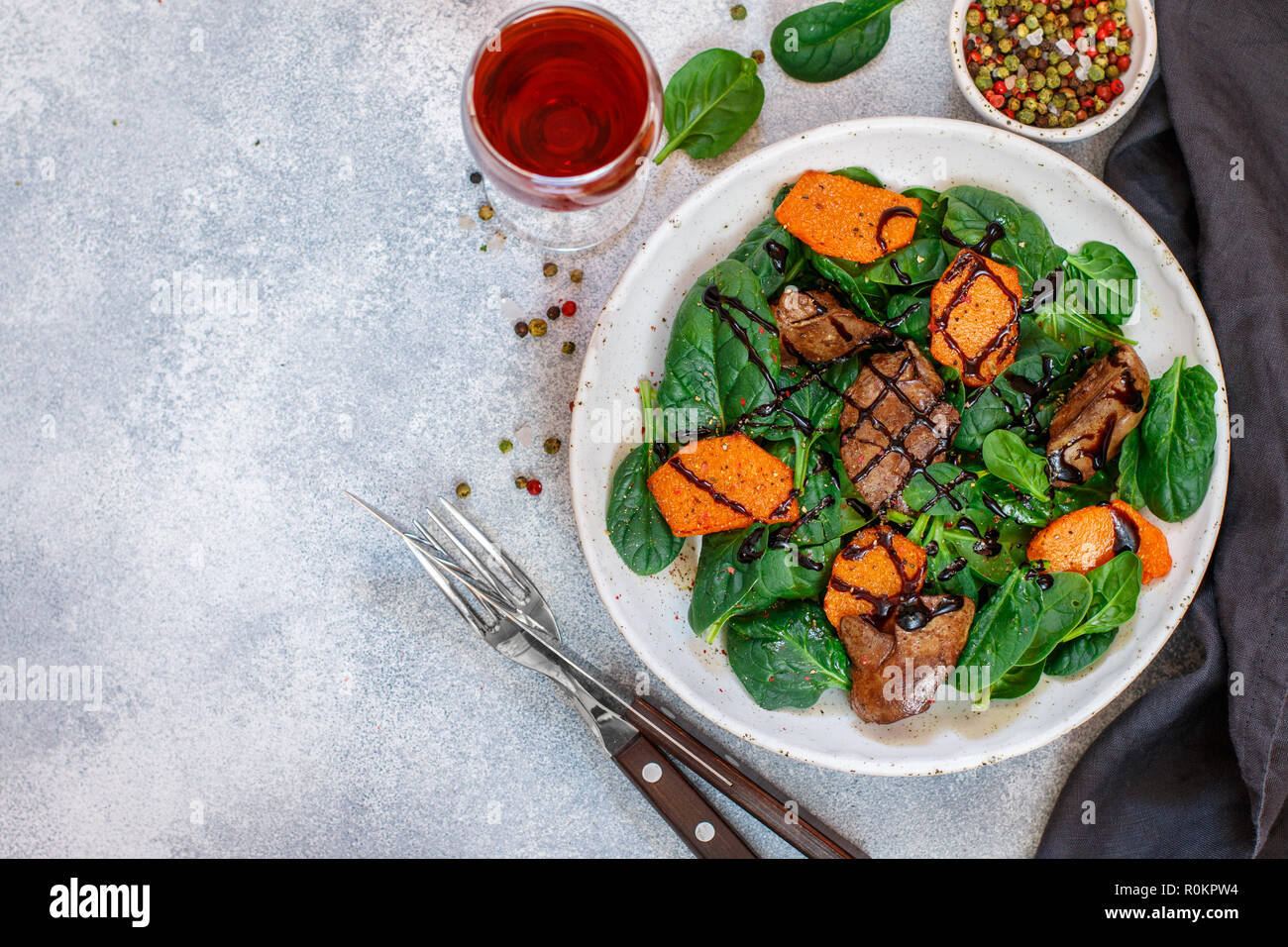 Salade tiède de foie de poulet cuit avec de la citrouille et aux épices et vinaigre balsamique. Délicieux dîner avec du vin rouge pour les gourmets. Selective focus, top vi Banque D'Images