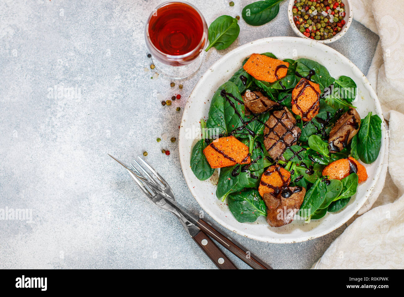 Salade tiède de foie de poulet cuit avec de la citrouille et aux épices et vinaigre balsamique. Délicieux dîner avec du vin rouge pour les gourmets. Selective focus, top vi Banque D'Images