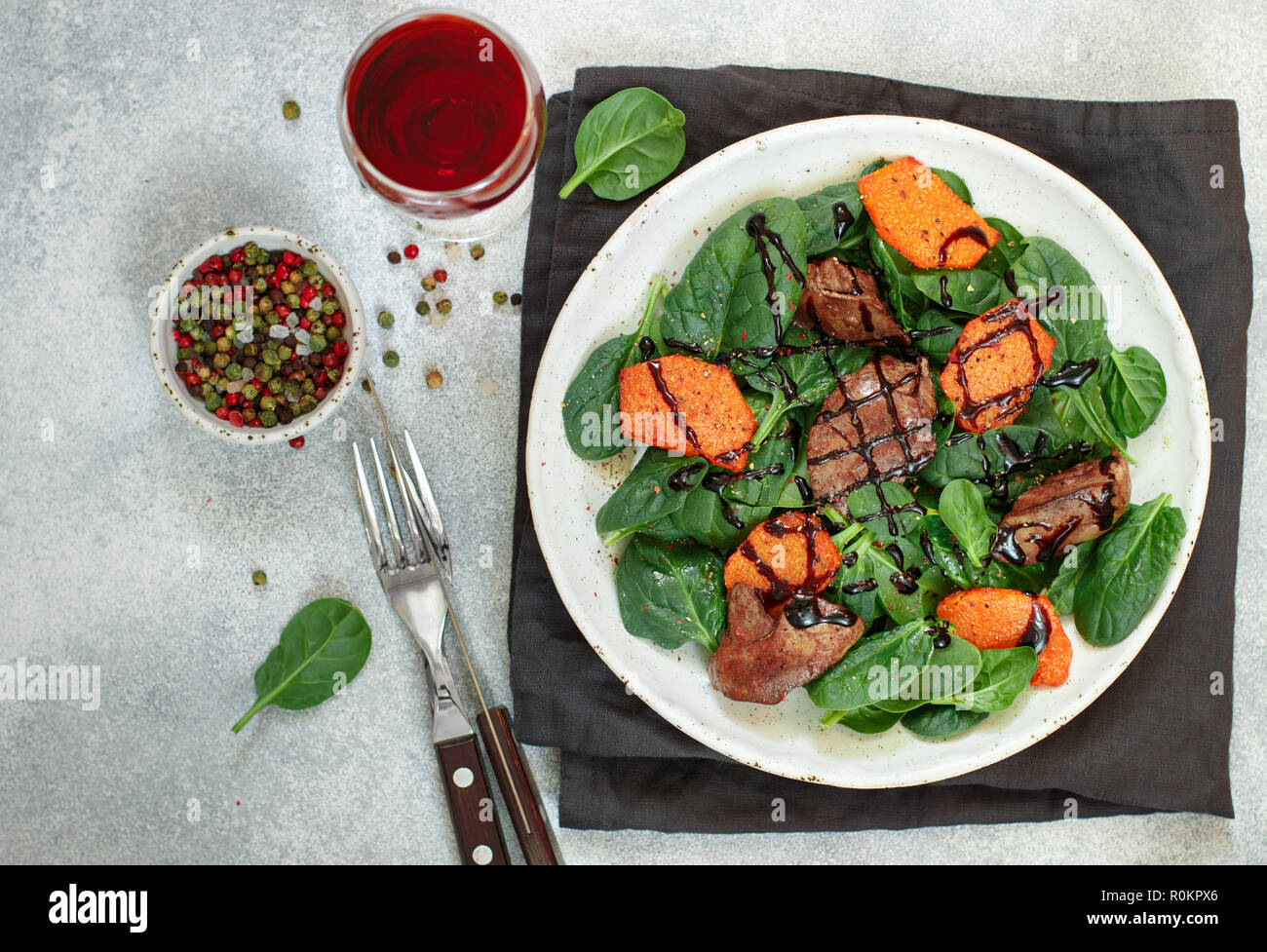Salade tiède de foie de poulet cuit avec de la citrouille et aux épices et vinaigre balsamique. Délicieux dîner avec du vin rouge pour les gourmets. Selective focus, top vi Banque D'Images