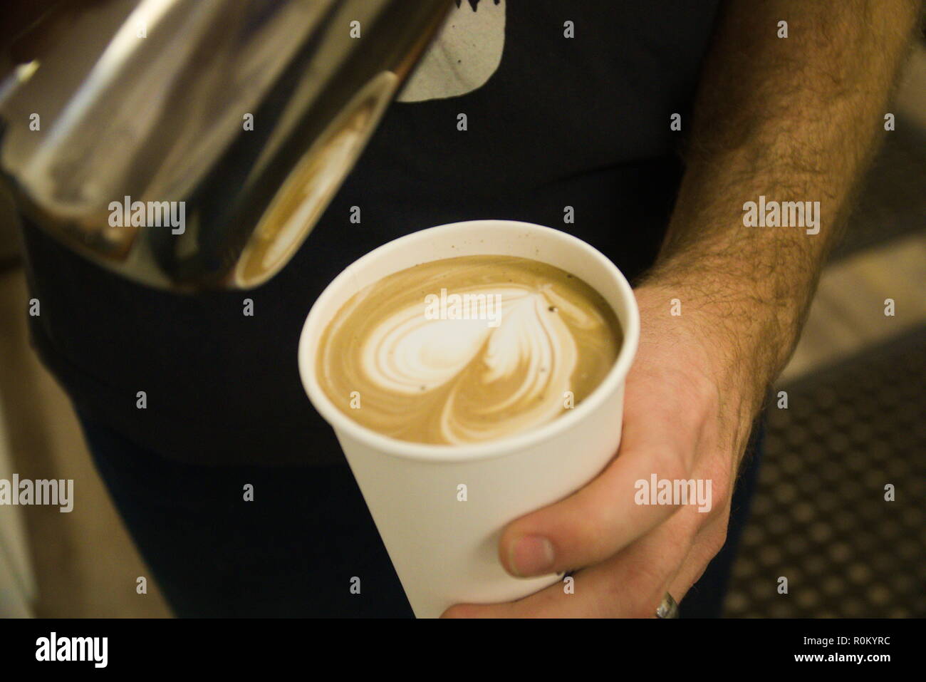 Un barista verse du lait chaud dans un café. Banque D'Images