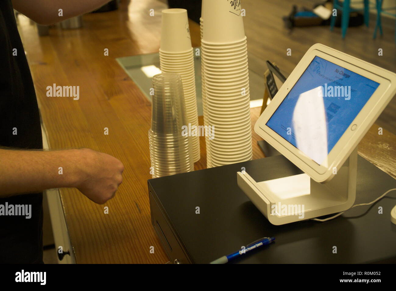Un barista vérifie un client dans un café. Banque D'Images