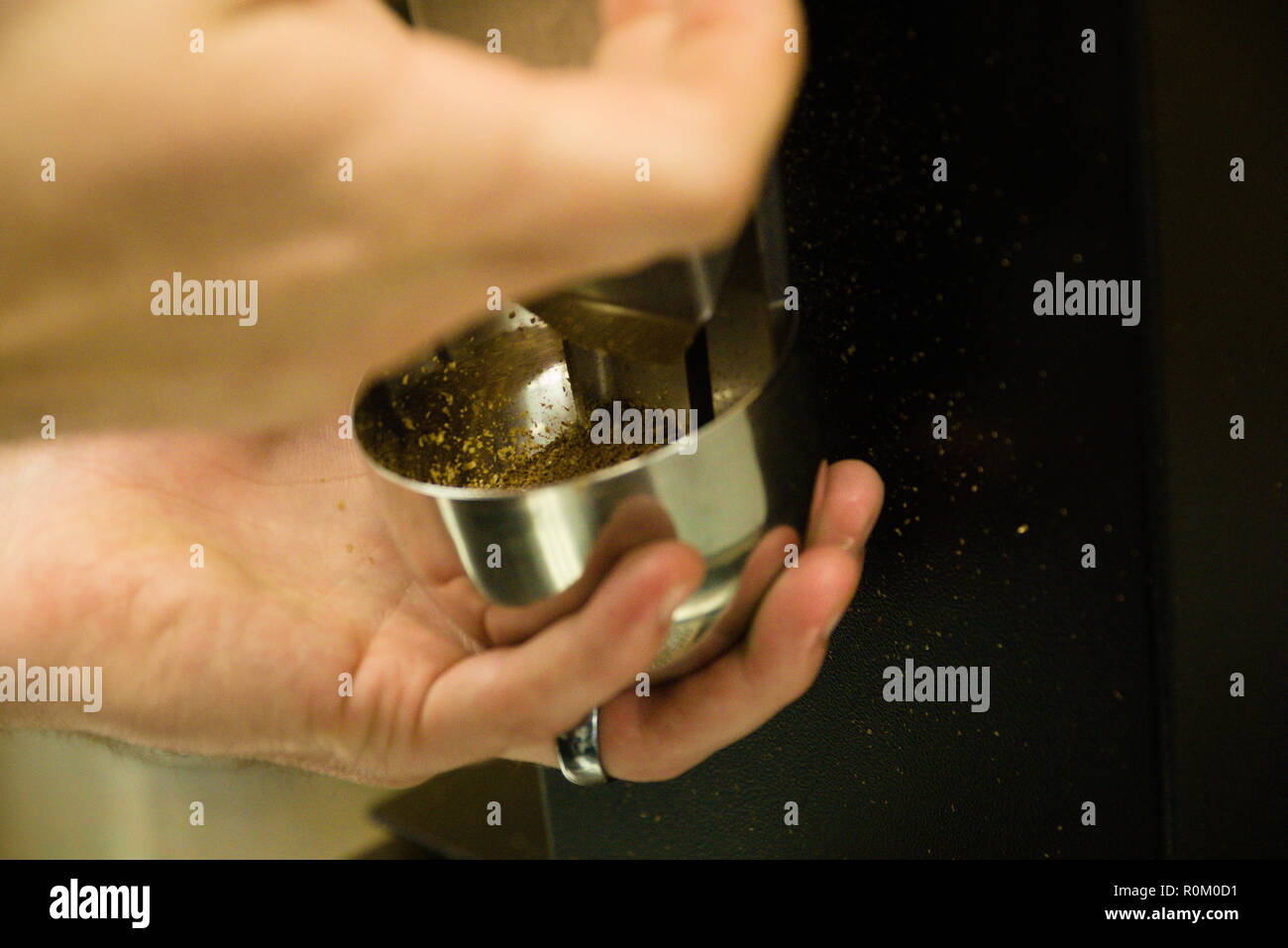 Un homme est titulaire d'un gobelet de métal et verser des grains de café. Banque D'Images
