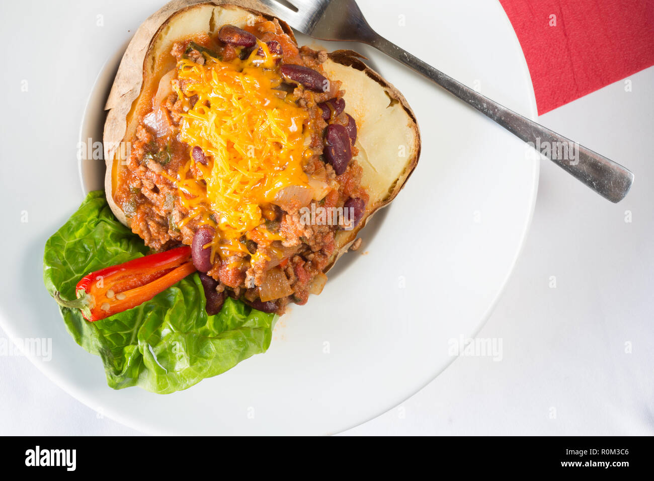 Pomme de terre cuite au four avec une veste de viande hachée surmontée de remplissage de chili avec du fromage râpé. Banque D'Images