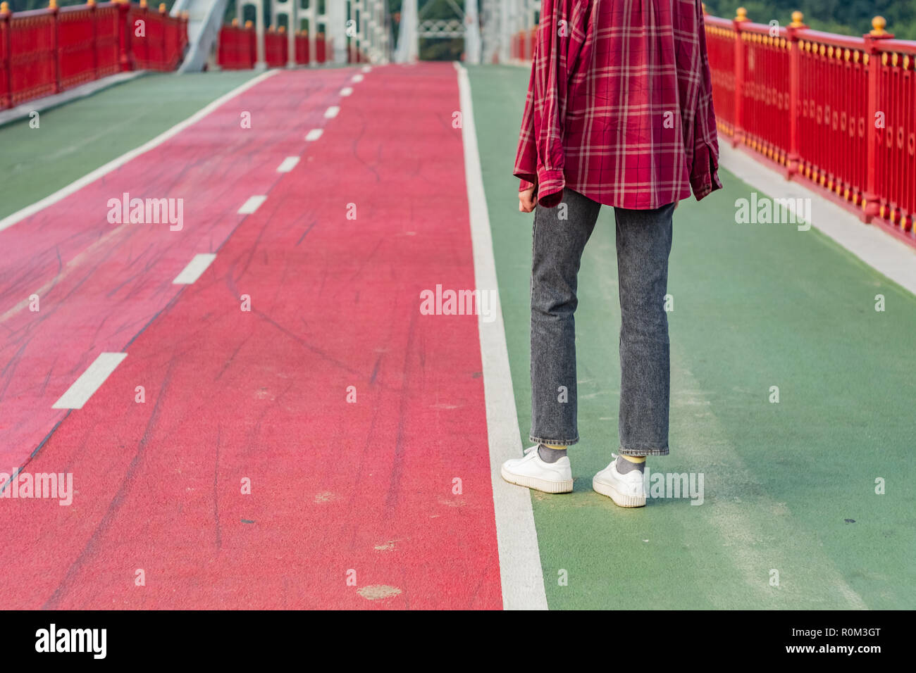 Figure féminine debout sur un pont pour piétons peints en vert et rouge. Banque D'Images