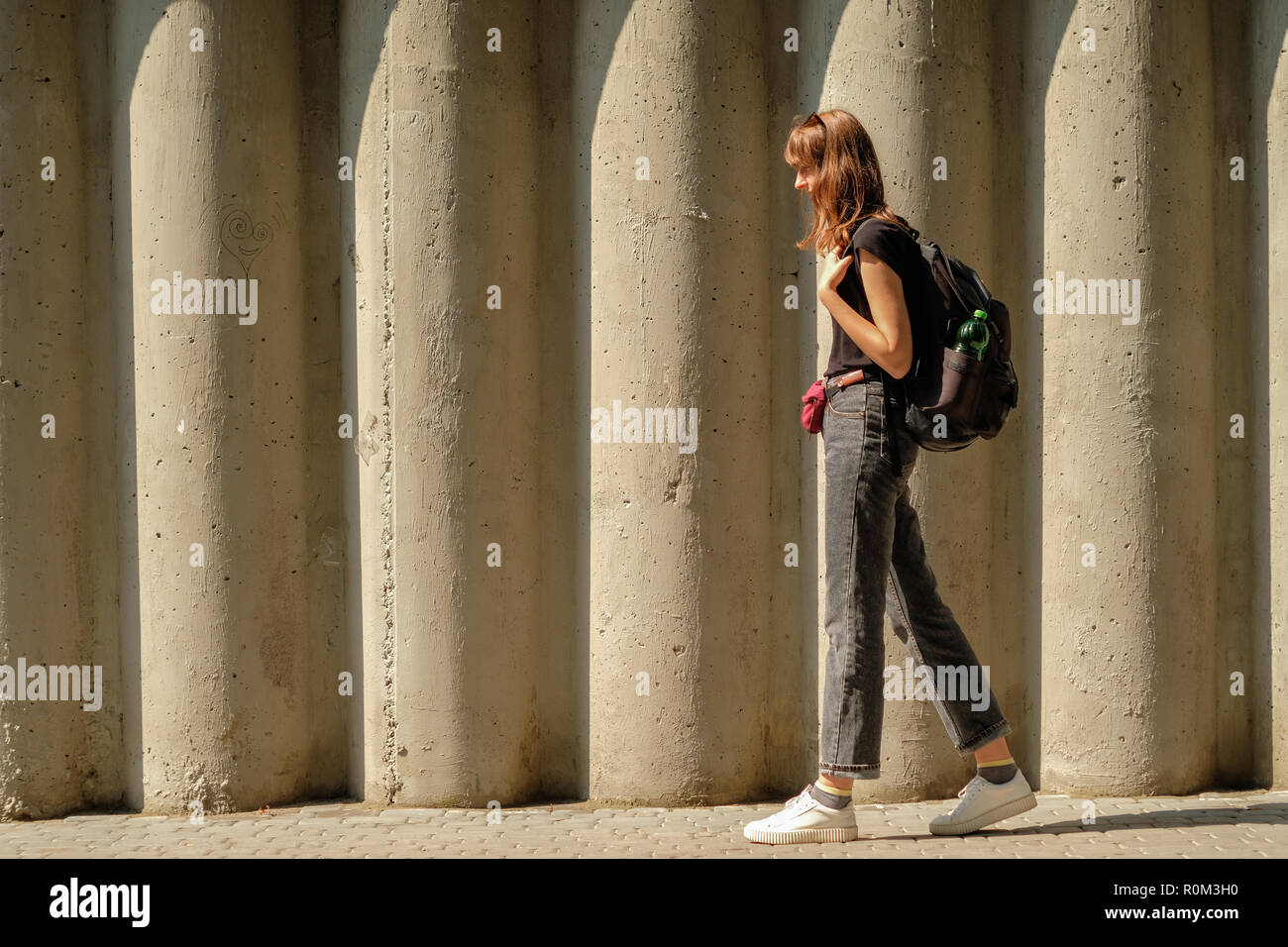 Femme marche sur un mur de béton en plein soleil. Banque D'Images