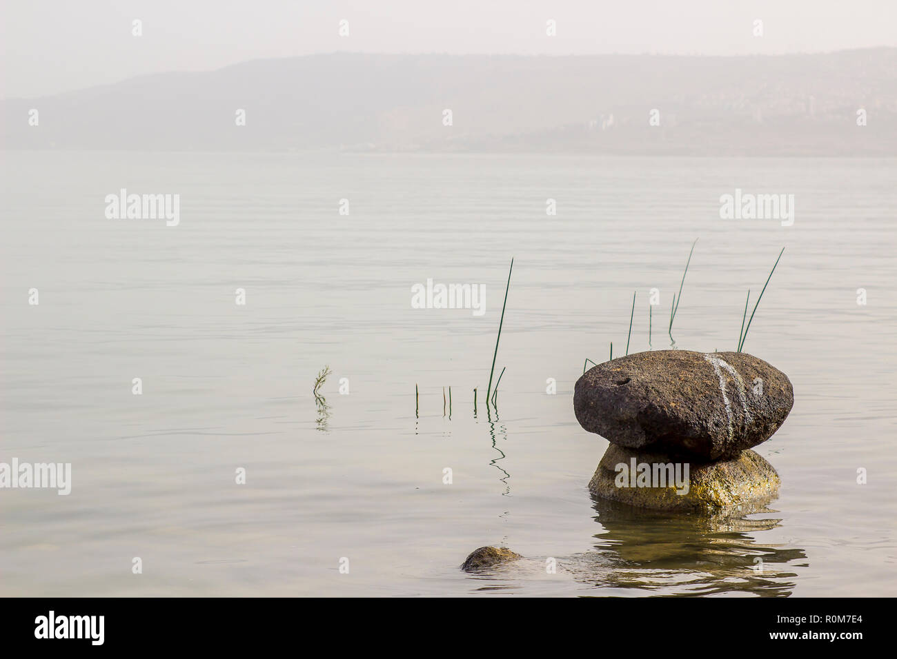 3 mai 2018 Rochers entassés ensemble dans un calme plat peu profondes de la mer de Galilée Israël Israël par une chaude après-midi brumeux Banque D'Images