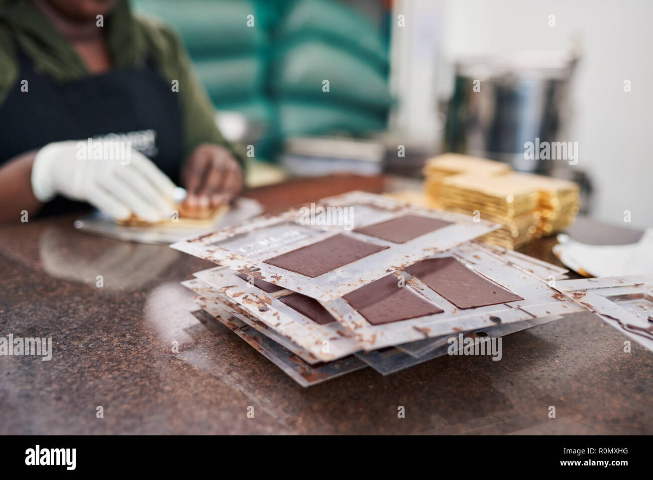 Les barres de chocolat emballage travailleur à partir de moules en papier doré Banque D'Images
