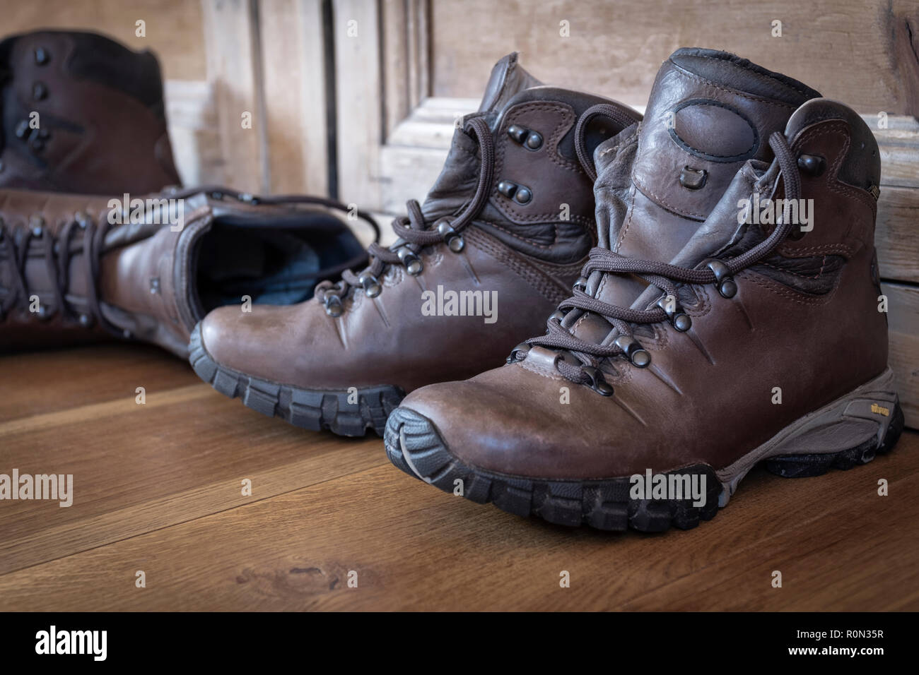 Deux paires de bottes de randonnée en cuir sur un plancher en bois. Banque D'Images