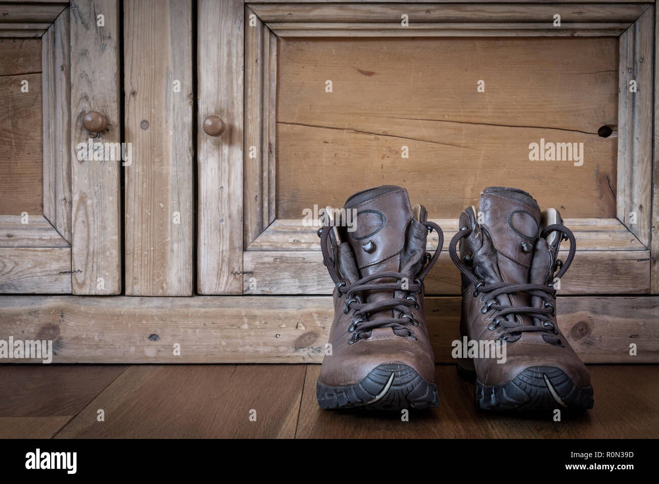 Une paire de bottes de randonnée en cuir sur un plancher en bois. Banque D'Images