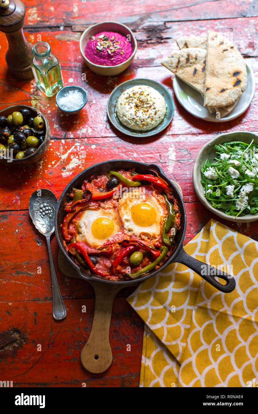 Plat moyen-orientale de Shakshuka à la feta salade de roquette, hoummos, olives et pain pitta grillé Banque D'Images