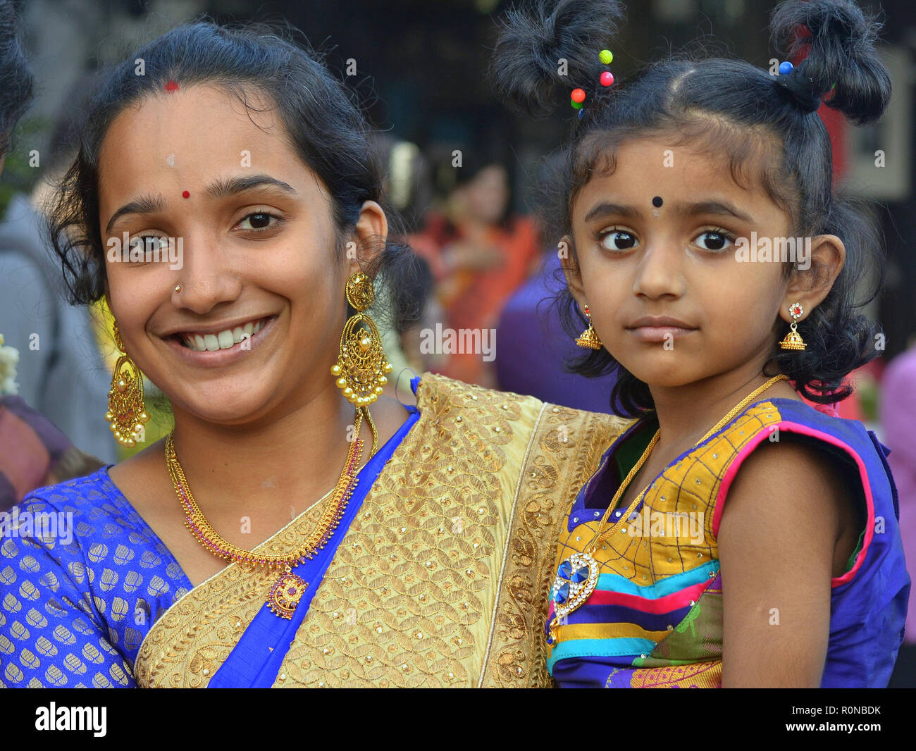 Habillé, jeune femme indienne de Malaisie avec sa petite fille sourit pendant Thaipusam. Banque D'Images