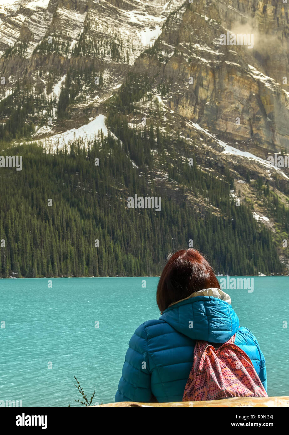 LAKE LOUISE, ALBERTA, CANADA - Juin 2018 : Personne qui siège seul looking out at Lake Louise en Alberta, Canada, Banque D'Images