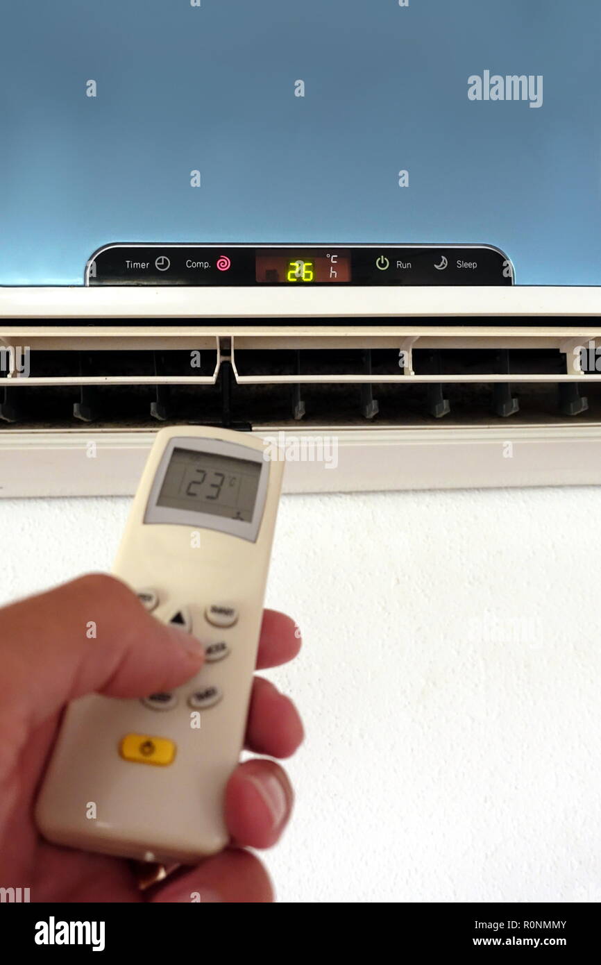 Quelqu'un la modification des paramètres d'un AC ou d'unité d'air conditionné avec télécommande - l'accent sur l'unité murale Banque D'Images