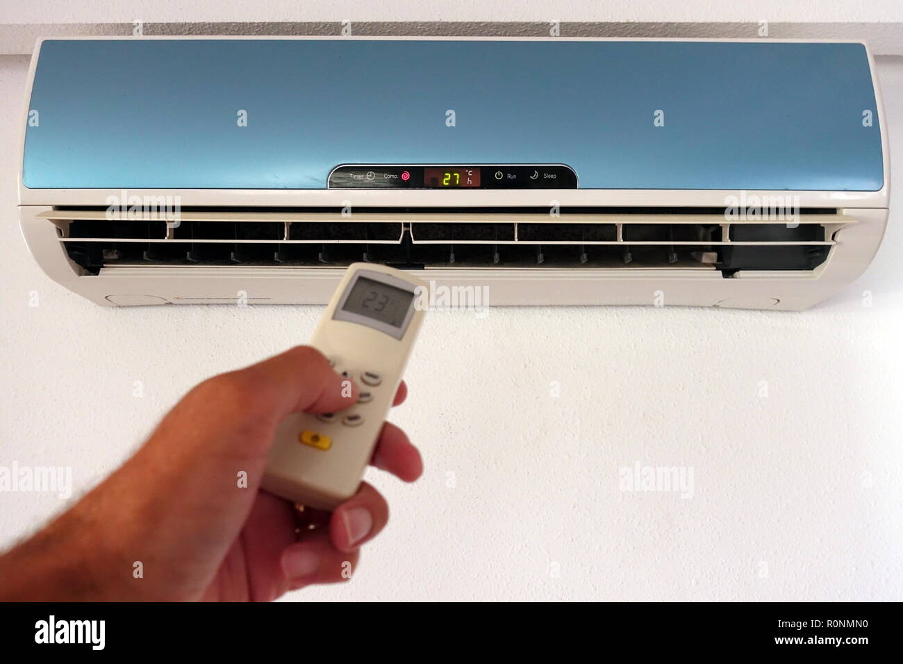 Quelqu'un la modification des paramètres d'un AC ou d'unité d'air conditionné avec télécommande - l'accent sur l'unité murale Banque D'Images