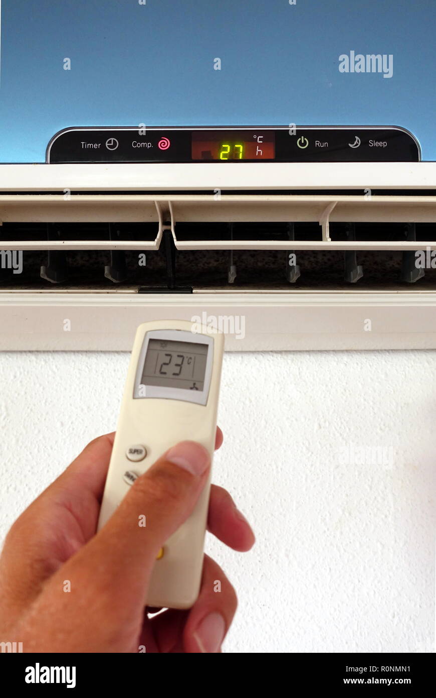 Quelqu'un la modification des paramètres d'un AC ou d'unité d'air conditionné avec télécommande - l'accent sur l'unité murale Banque D'Images