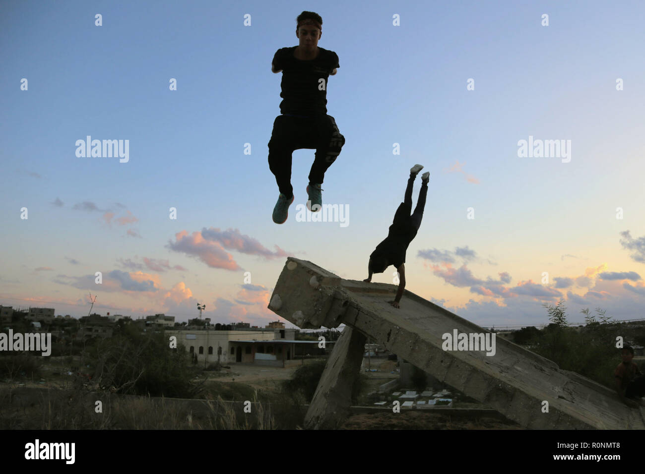 Deux jeunes Palestiniens sont vus au cours de leur haut saut Parkour pratique de l'immeuble ravagé par la guerre à Gaza. Gaza est l'un des plus hauts taux de chômage des jeunes dans le monde avec plus de 80 % des jeunes de moins de 30 ans sont sans emploi, Parkour est un des moyens pour les jeunes de passer leurs longues après-midi et se maintenir en forme. Banque D'Images
