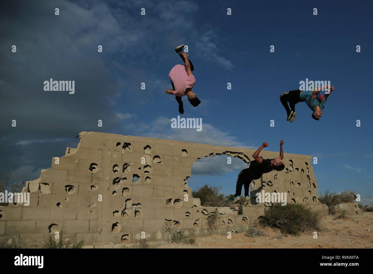 Trois jeunes Palestiniens sont vus pendant leur saut Parkour pratique de l'immeuble ravagé par la guerre à Gaza. Gaza est l'un des plus hauts taux de chômage des jeunes dans le monde avec plus de 80 % des jeunes de moins de 30 ans sont sans emploi, Parkour est un des moyens pour les jeunes de passer leurs longues après-midi et se maintenir en forme. Banque D'Images