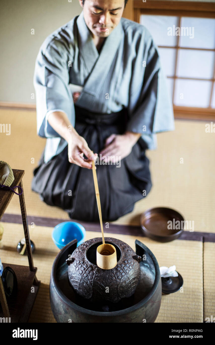 La cérémonie du thé japonaise traditionnelle, l'homme portant un kimono assis sur le plancher, en utilisant un Hishaku, une louche de bambou, de verser de l'eau chaude. Banque D'Images