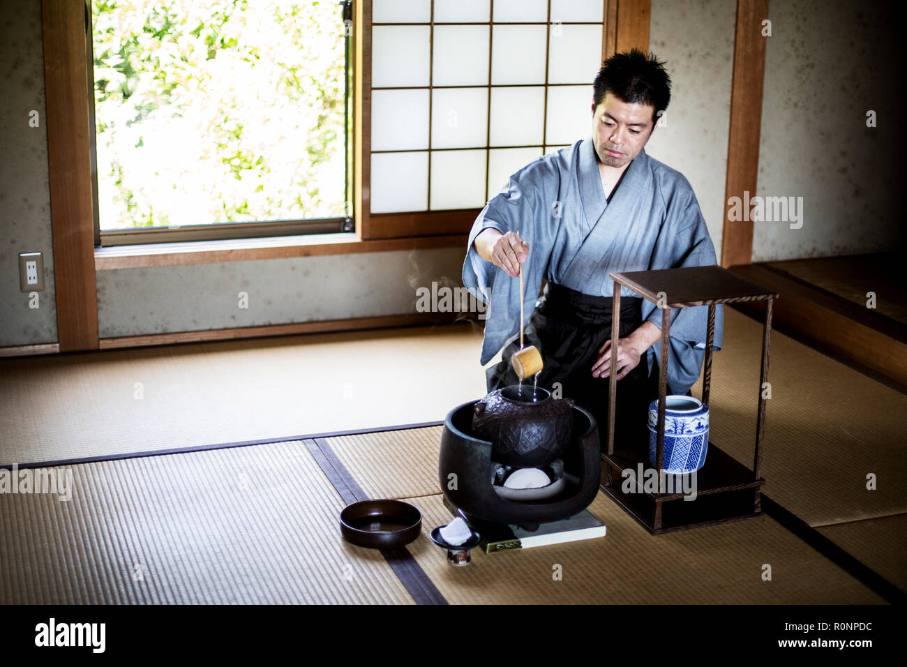 La cérémonie du thé japonaise traditionnelle, l'homme portant un kimono assis sur les tatamis à l'aide d'une louche Hishaku, un bambou, de verser de l'eau chaude. Banque D'Images